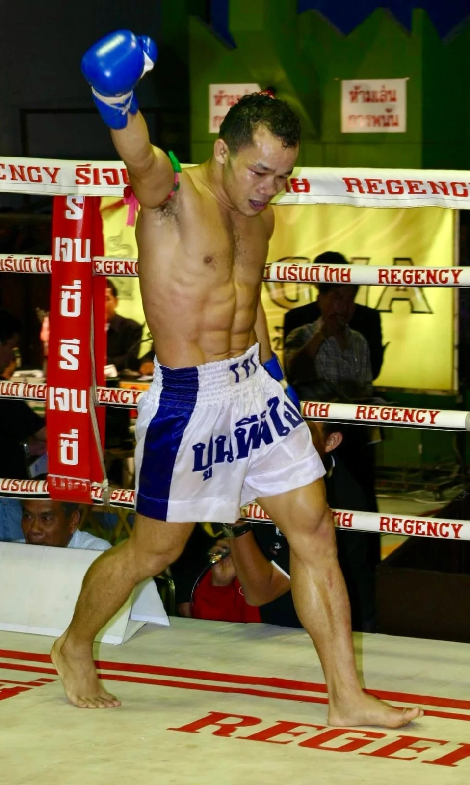 Archival photograph of a boxer with blue gloves in a boxing ring