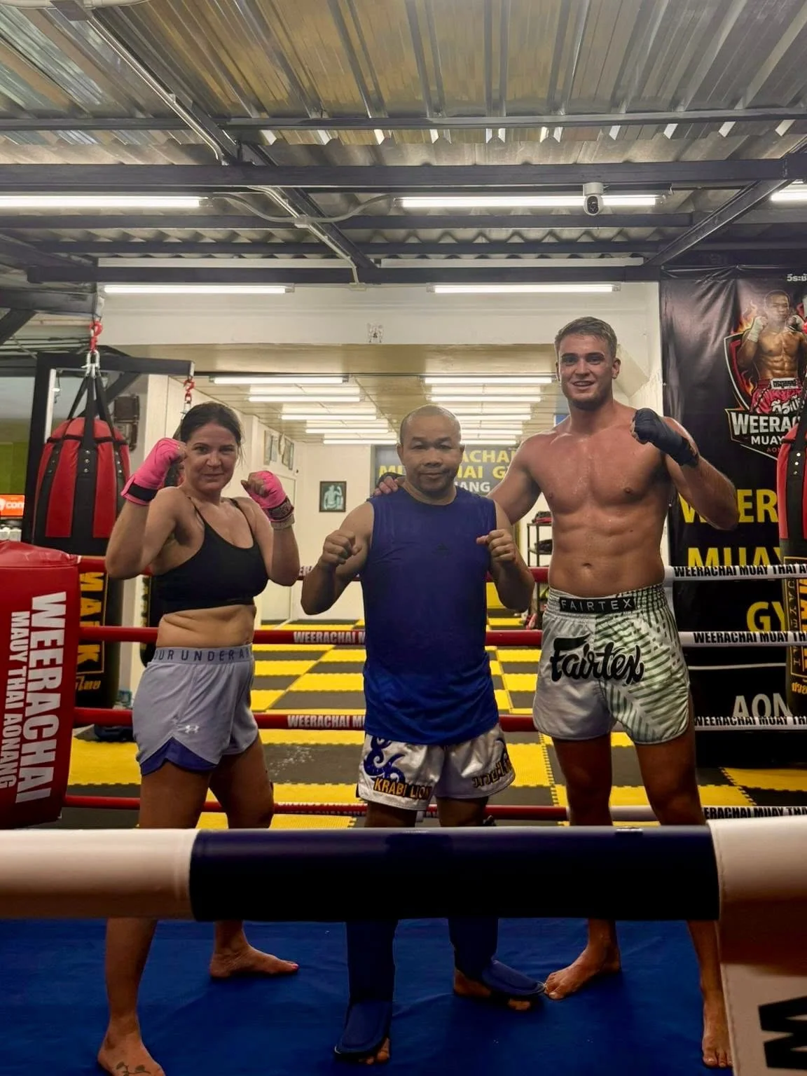 Three people posing together inside the gym’s boxing ring